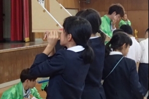 写真：体育館において測量体験学習（三角定規を使った高低差測量）